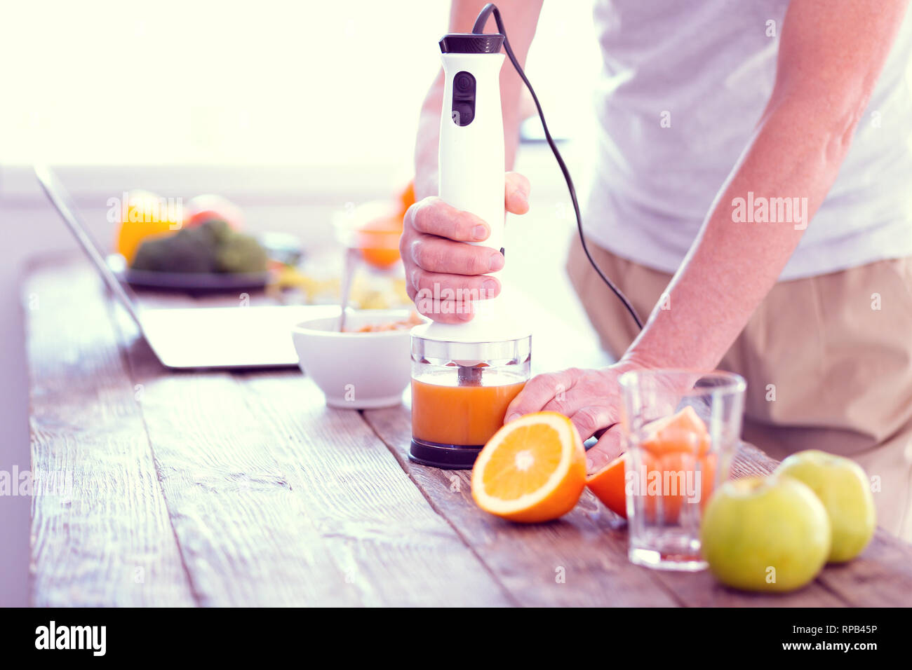 Mann stand in der Nähe des Tisches während des Mixens Orangen und Äpfel zu Saft Stockfoto