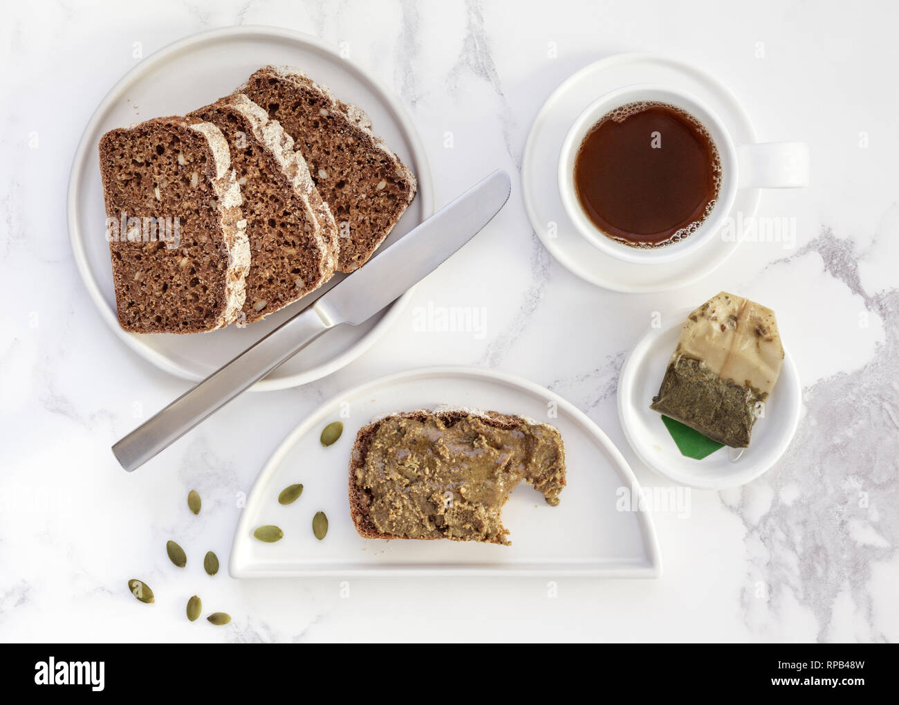 Hausgemachte ryebread mit Kürbis Samen ausbreiten und eine Tasse grüner Tee Stockfoto