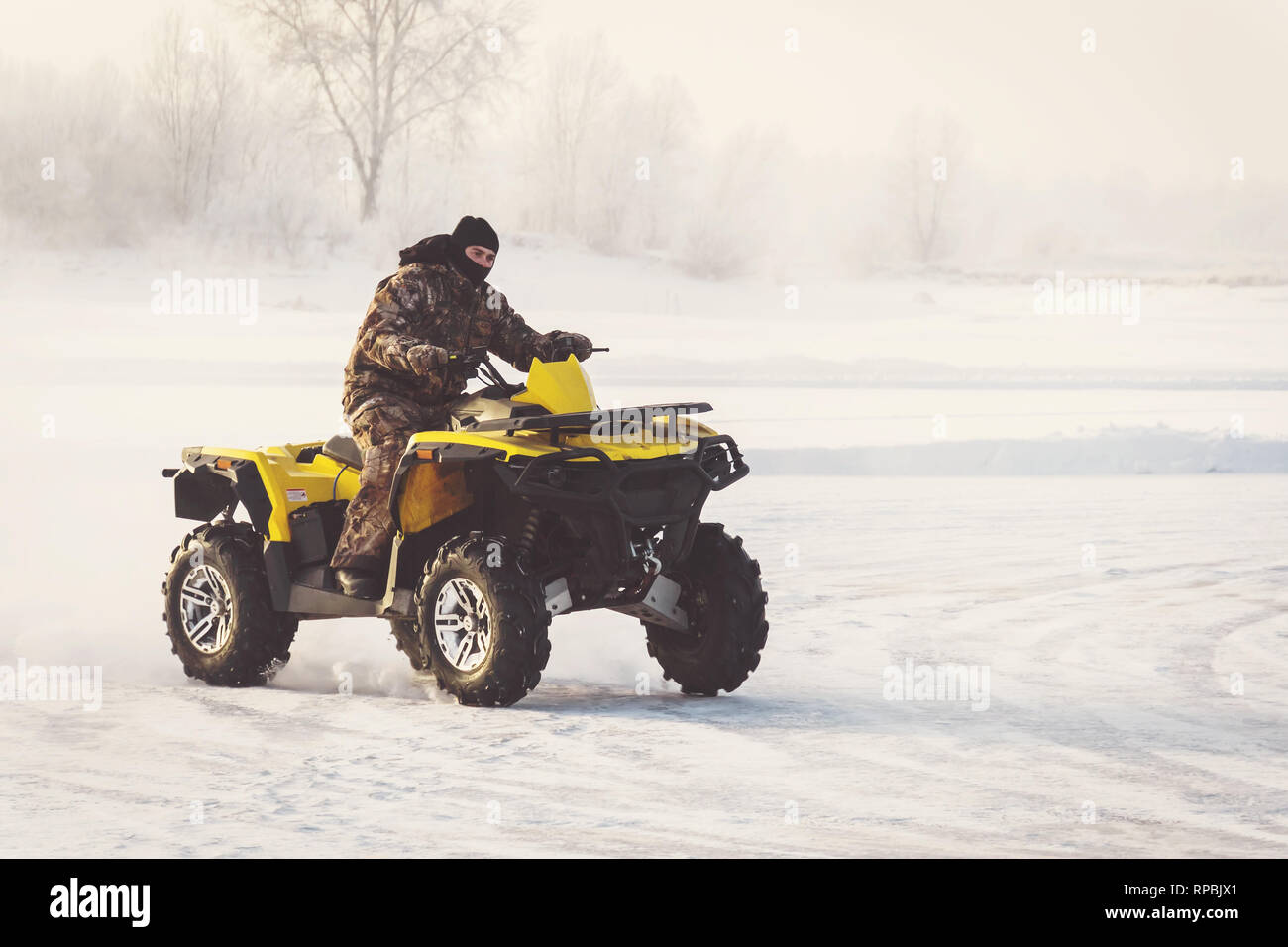 ATV Fahren auf einer verschneiten Landstraße. Winter Event auf dem Quad Extreme winter Motor Sport. schöne Winterlandschaft, Feld und Bäume. Extreme Winter Spaß Stockfoto