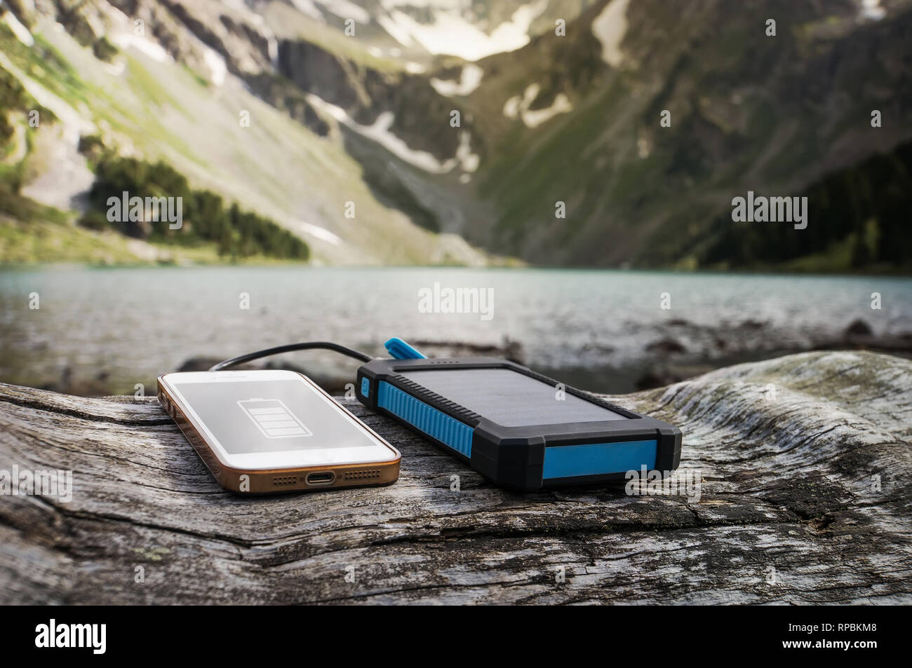 Akku Solar Energy Device auf dem Hintergrund der schönen Berglandschaft. Smart Phone aus der Solar Batterie aufladen. Stockfoto