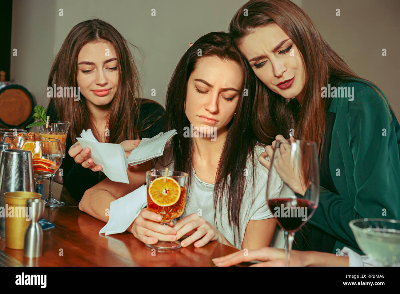 Stress. Weibliche Freunde haben eines Drinks an der Bar. Sie sitzen an einem Holztisch mit Cocktails. Sie sind legere Kleidung. Freunde tröstlich und beruhigend eine schreiende mädchen Stockfoto