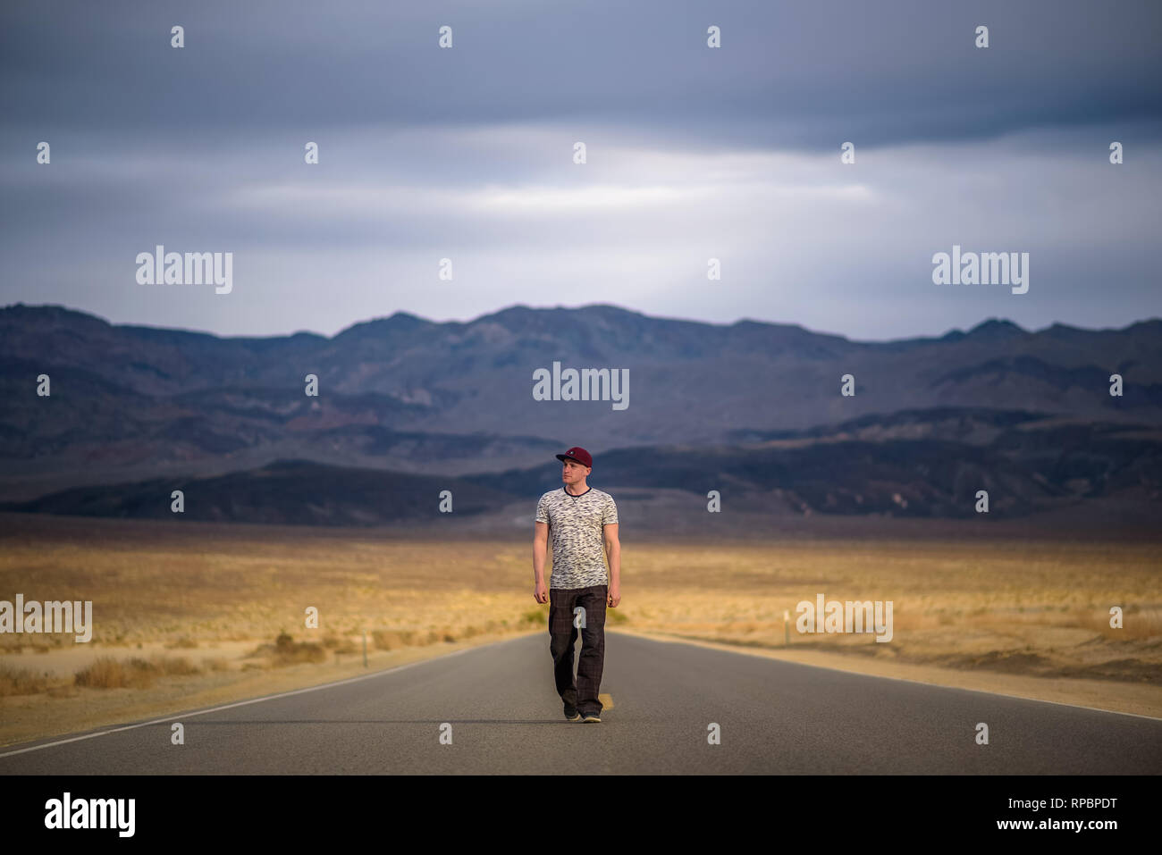 Junger Mann alleine durch eine leere Straße in der Wüste von Death Valley Stockfoto