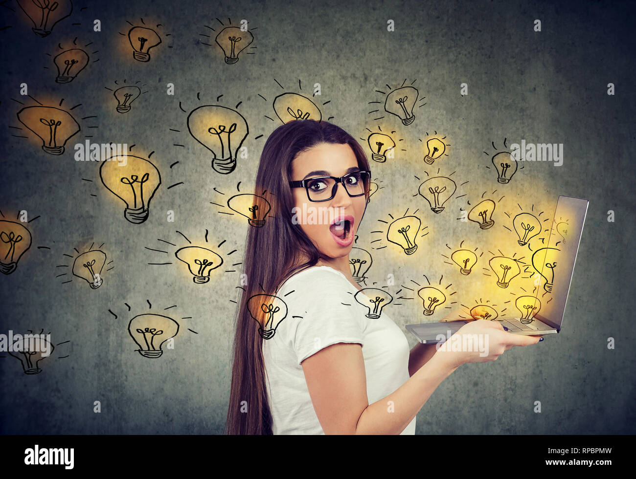 Junge Frau mit einem Laptop mit brillanten Ideen Glühbirnen fliegen Überrascht Stockfoto