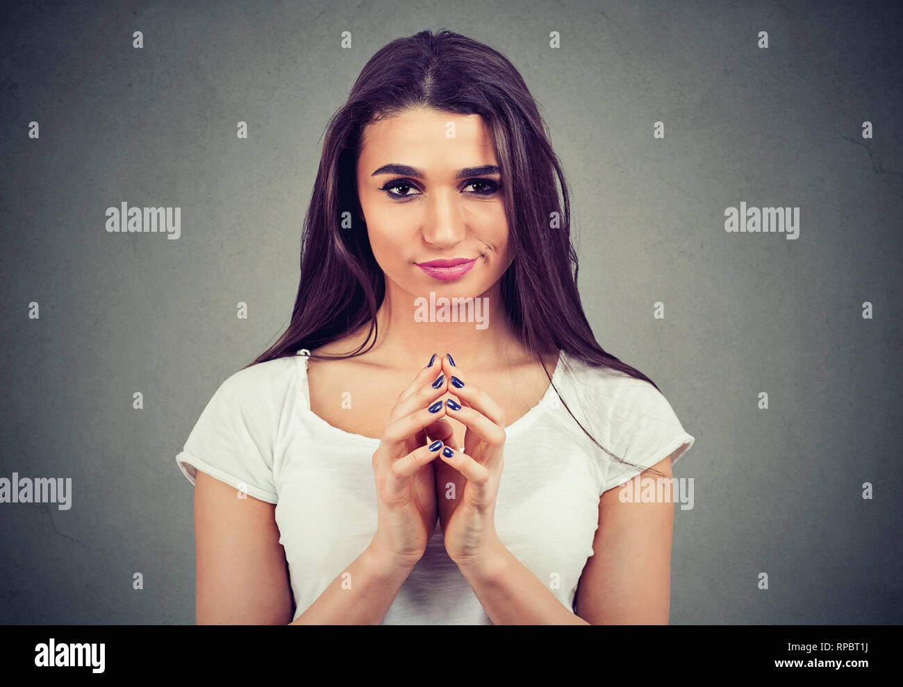 Nahaufnahme von einem hinterhältigen Intrigen junge Frau plotten etwas auf grauem Hintergrund. Negative menschliche Emotionen Gefühle Stockfoto