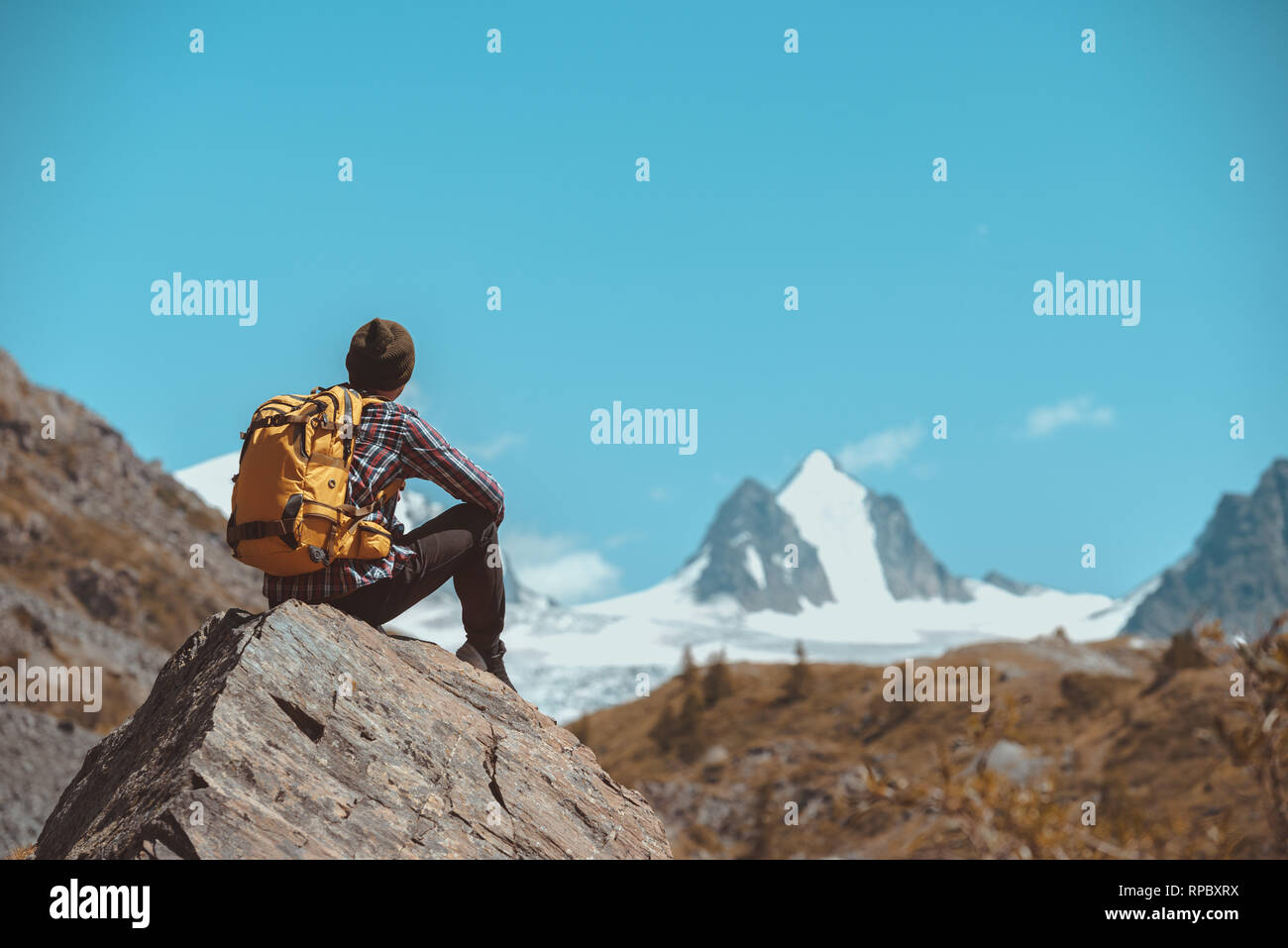 Mann Wanderer mit Rucksack sitzt auf Big Rock und sieht am Weißen Berg mit Gletscher Stockfoto