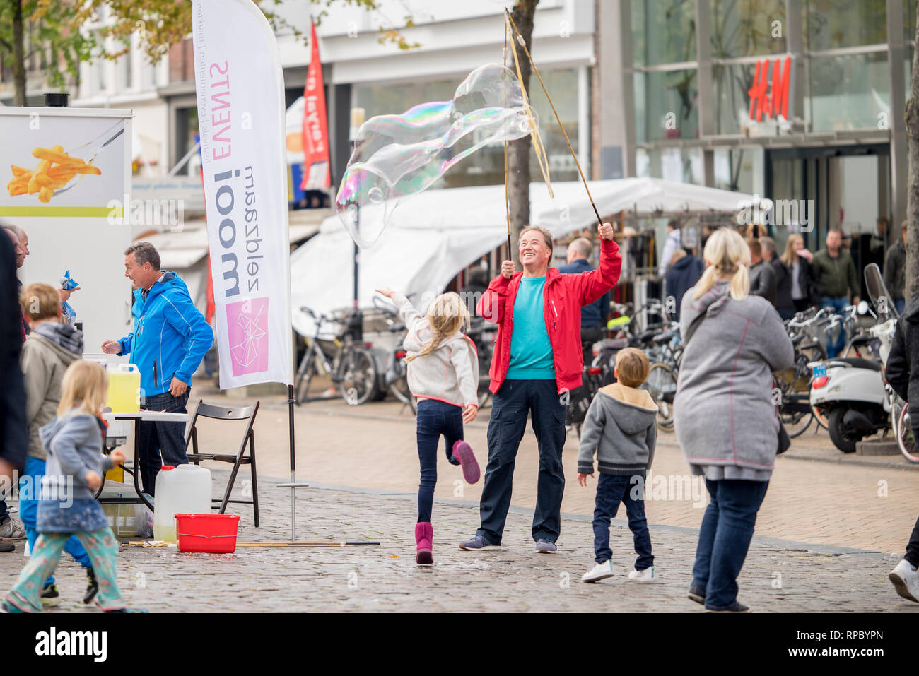 Menschen mit riesigen Seifenblasen zu einem Fischmarkt in Groningen, die die Aufmerksamkeit der Kinder spielerisch Fänge, springt es Stockfoto