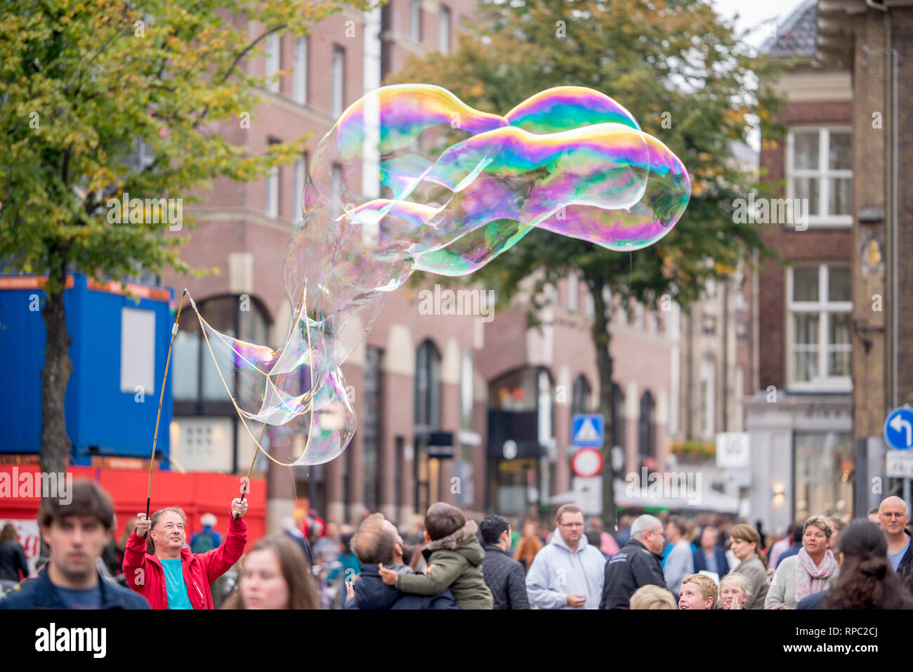 Menschen mit riesigen Seifenblasen zur Unterhaltung der Leute auf dem Markt und vor allem der Fänge, die Aufmerksamkeit von Kindern an der Groningen Samstag mark Stockfoto
