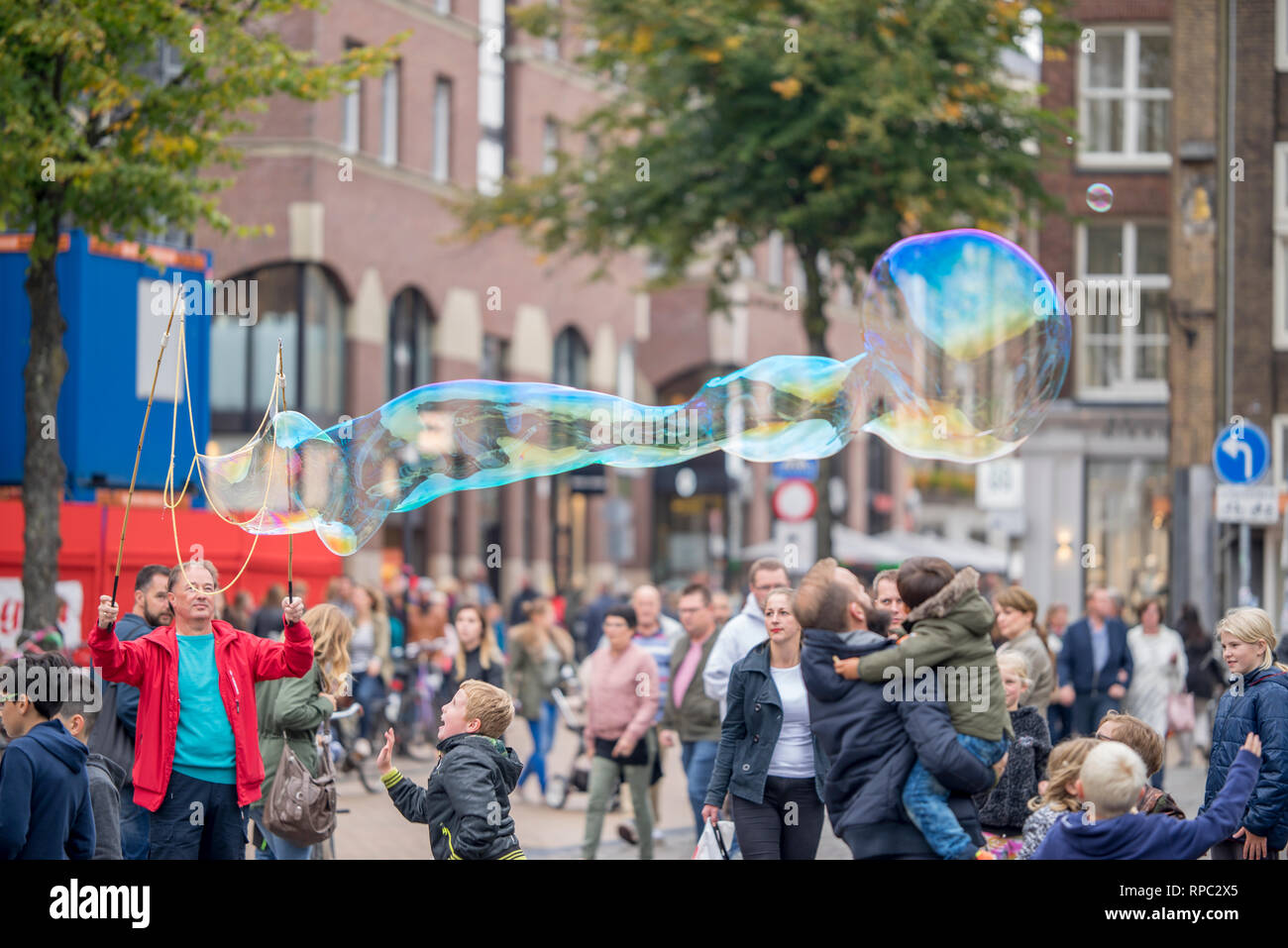 Menschen mit riesigen Seifenblasen zur Unterhaltung der Leute auf dem Markt und vor allem der Fänge, die Aufmerksamkeit von Kindern an der Groningen Samstag mark Stockfoto