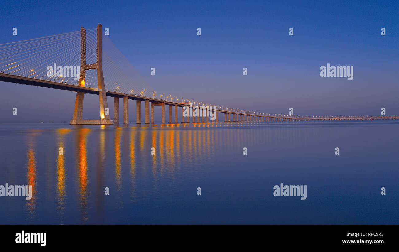 Elegante steel Bridge bei Nacht vorbei an Kilometer über große ruhige Fluss Wasser Stockfoto