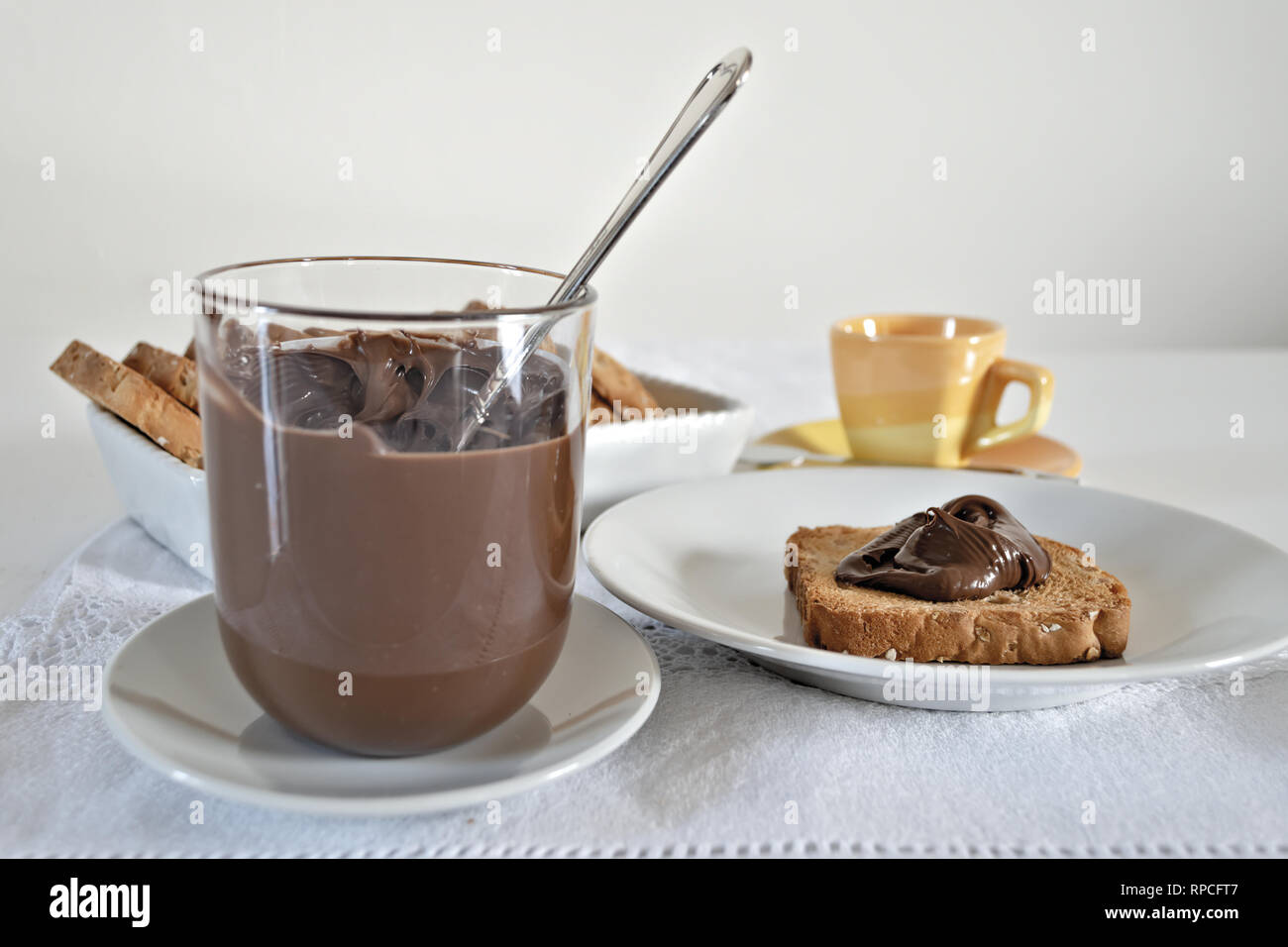 Fette Biscottate con Crema di Cacao al nocciole con bicchiere Fronte Stockfoto