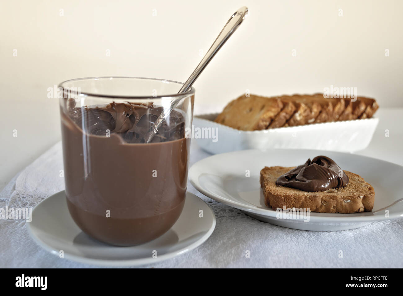 Fette Biscottate con Crema di Cacao al nocciole con bicchiere Fronte altra versione Stockfoto
