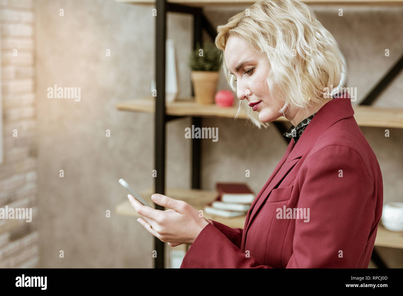 Ernsthafte blonde Frau starrte der Bildschirm des Smartphones Stockfoto