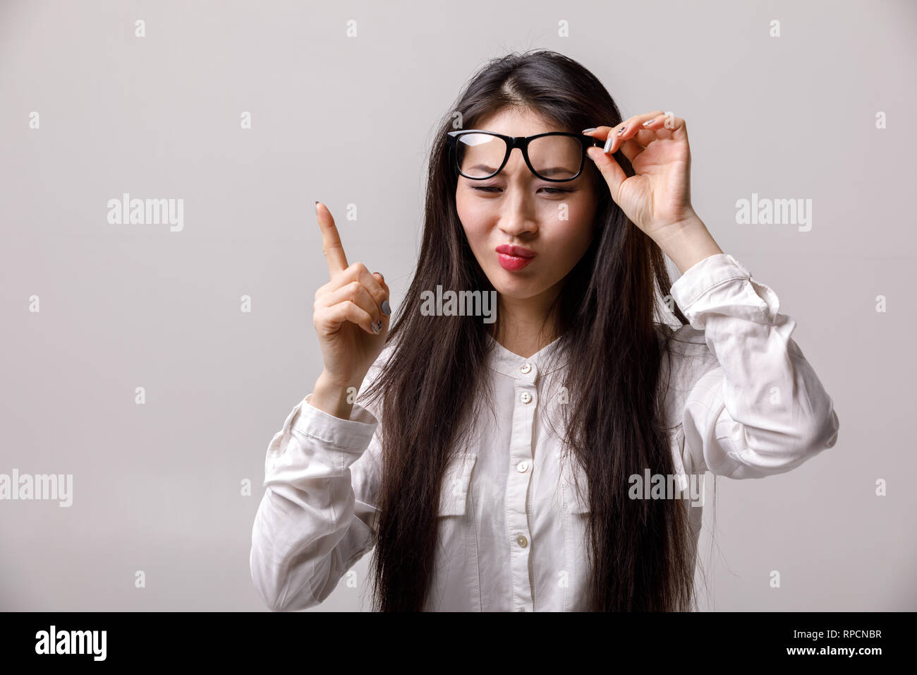 Portrait von jungen asiatischen Frau in Gläsern und weißes Hemd mit einer guten Idee auf grauem Hintergrund. Emotionen Stockfoto
