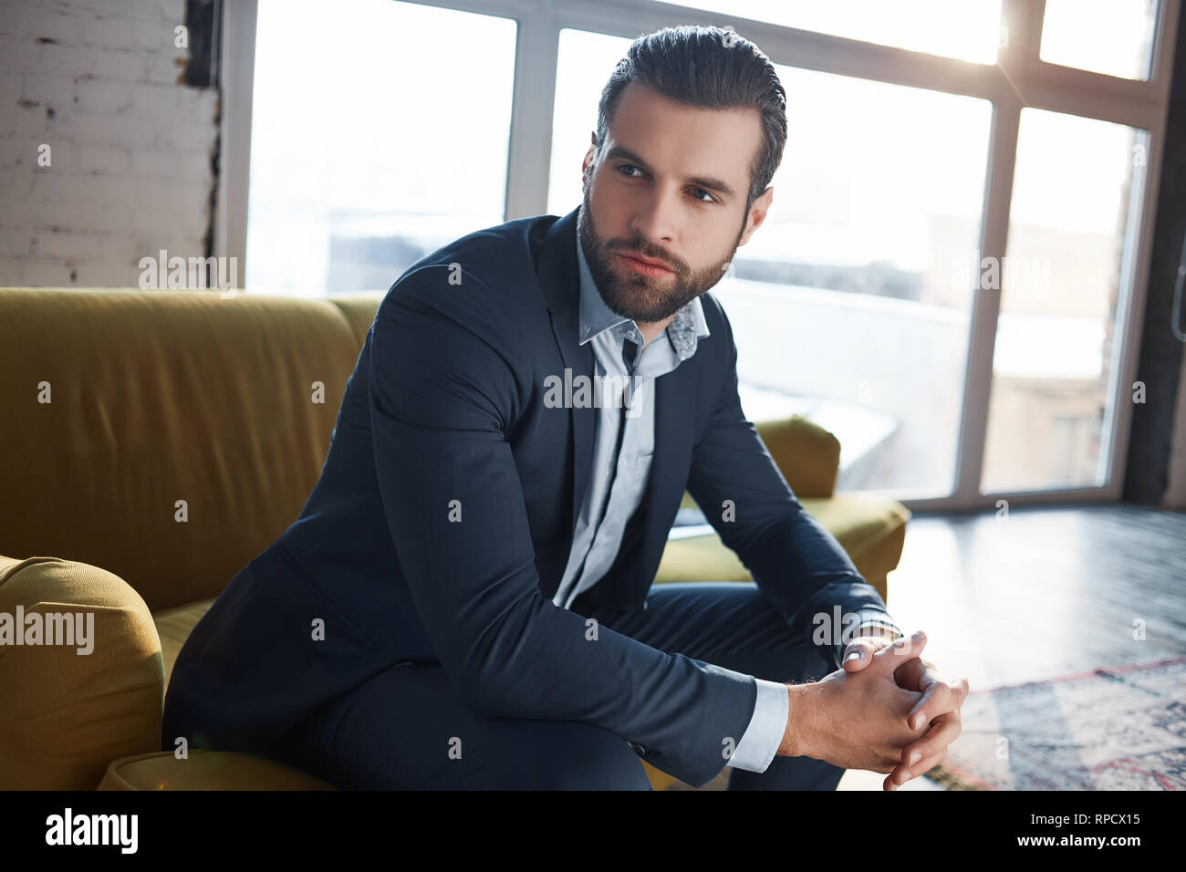 Verloren in Gedanken... Nachdenklich hübscher junger Geschäftsmann denkt über Business beim Sitzen auf dem Sofa in seinem Büro. Mode suchen. Geschäftskonzept. Stockfoto