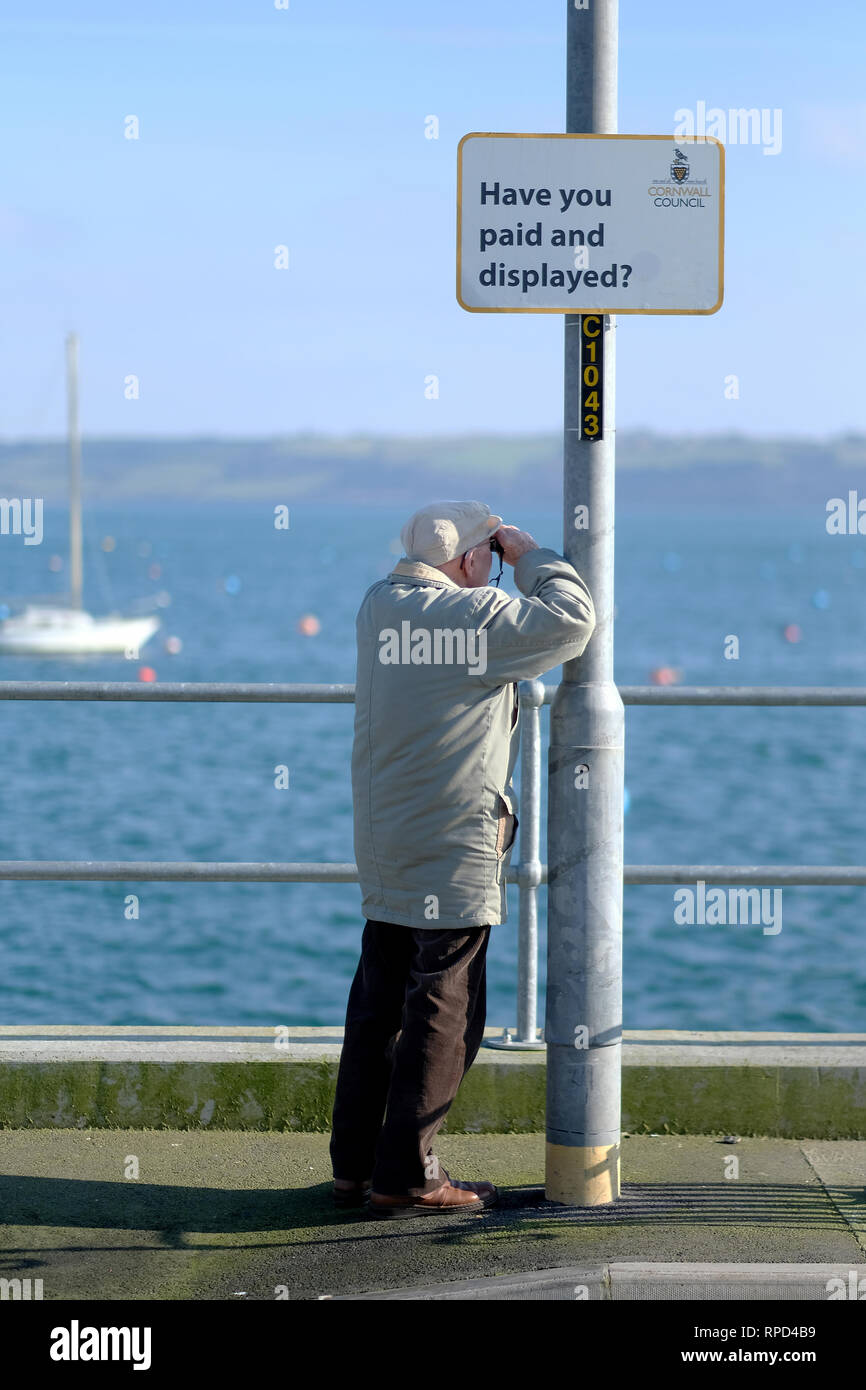 Ein pensionierter Mann durch das Meer durch ein Fernglas Stockfoto