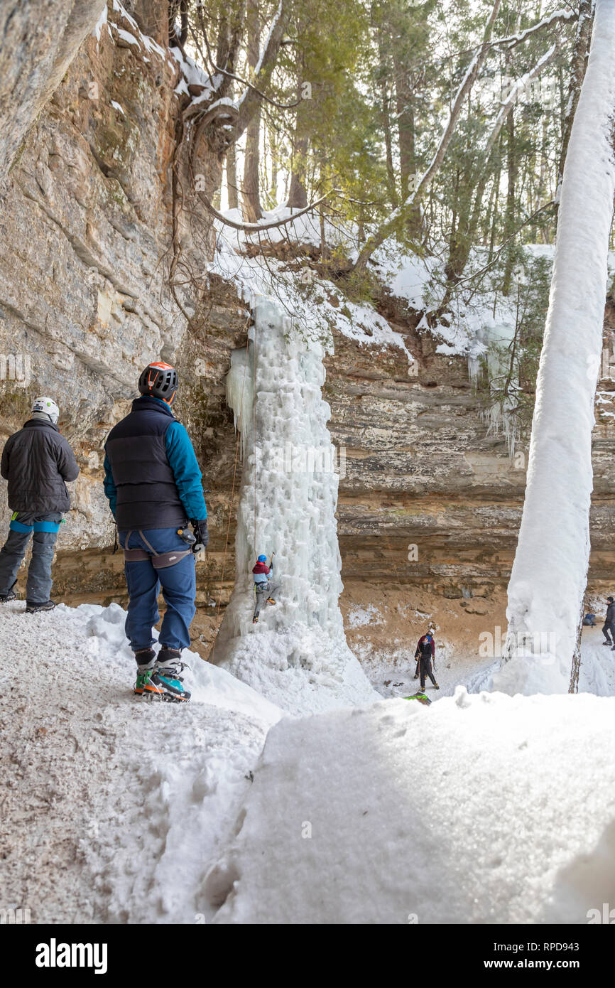 Munising, Michigan - Teilnehmer der jährlichen Michigan Eis Fest klettern, um einen gefrorenen Wasserfall in dargestellten Felsen National Lakeshore. Stockfoto