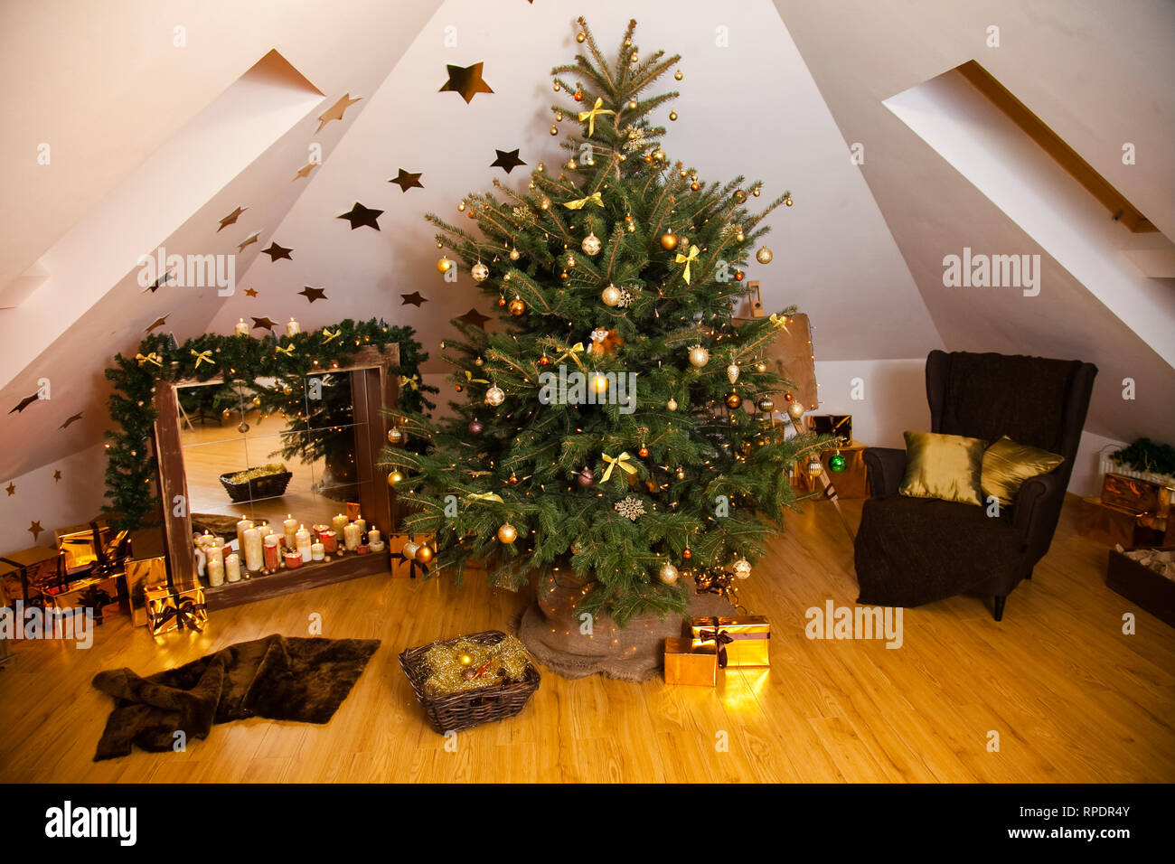 Weihnachtsschmuck im Studio, grosse natürliche Tanne Baum mit goldenen Kugeln, Schleifen und Schneeflocken, Kamin und Kerzen auf es und Braun gemütliche Ar Stockfoto