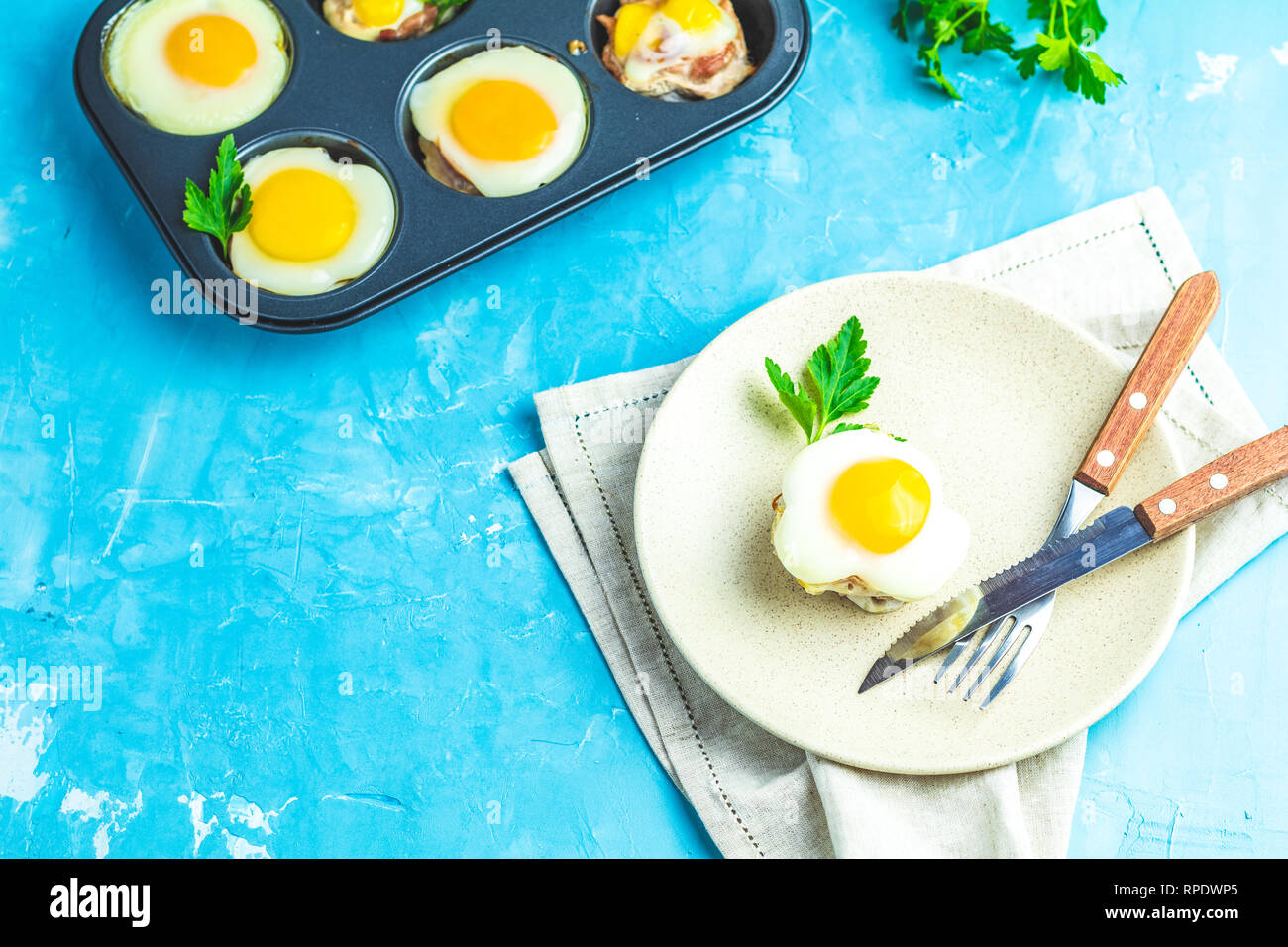 Gebackene Eier in der Licht- und Backformen. Portioniert Auflauf von Speck und Eier im italienischen Stil. Blauer Beton Tischfläche Hintergrund. Stockfoto