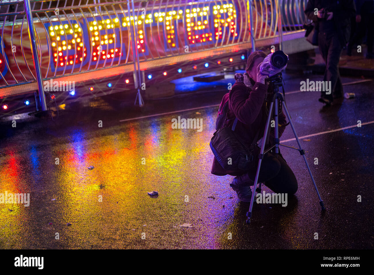 Junges Mädchen mit Kamera fotografieren Kirmes/Messe Lichter in der Nacht Stockfoto