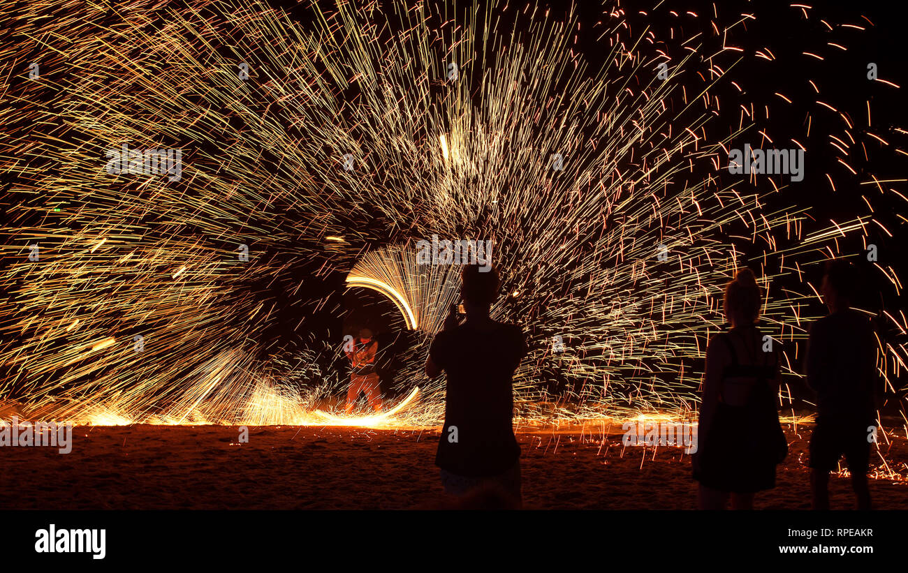 Funken fliegen spiralförmig in eine eindrucksvolle Anzeige an einem Strand Feuershow, Thailand. Stockfoto