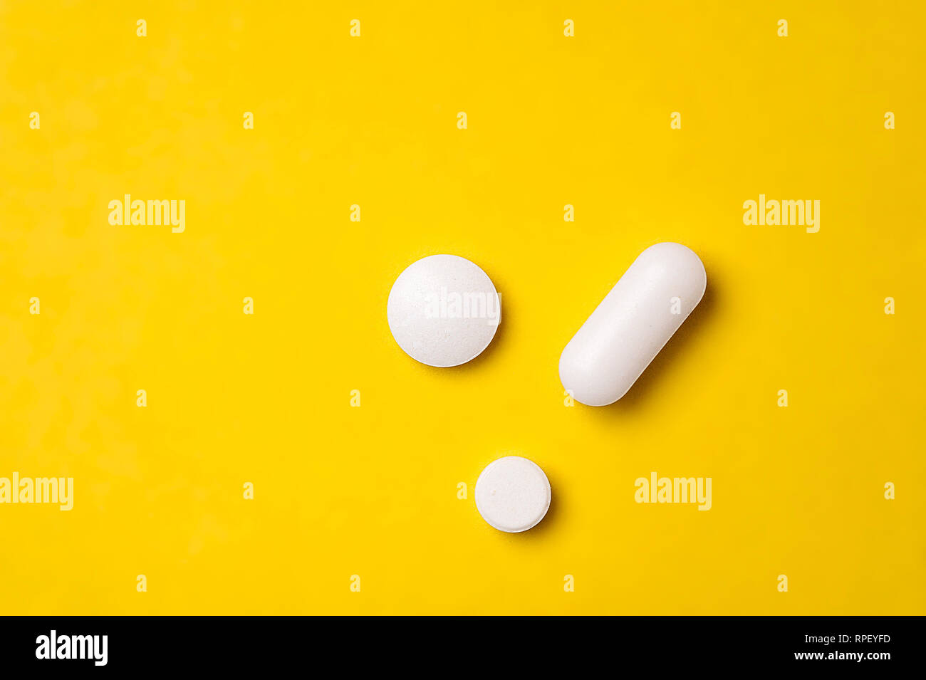 Weiße Tabletten auf gelben Hintergrund. Unterschiedliche Größe und Form der Ansicht von Oben Stockfoto