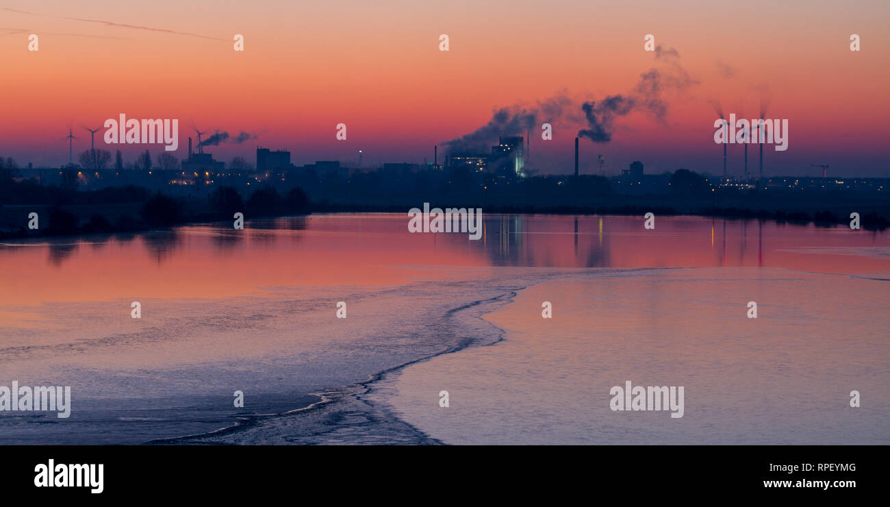 Panorama von Industriebauten und Windkraftanlagen bei Sonnenaufgang Stockfoto