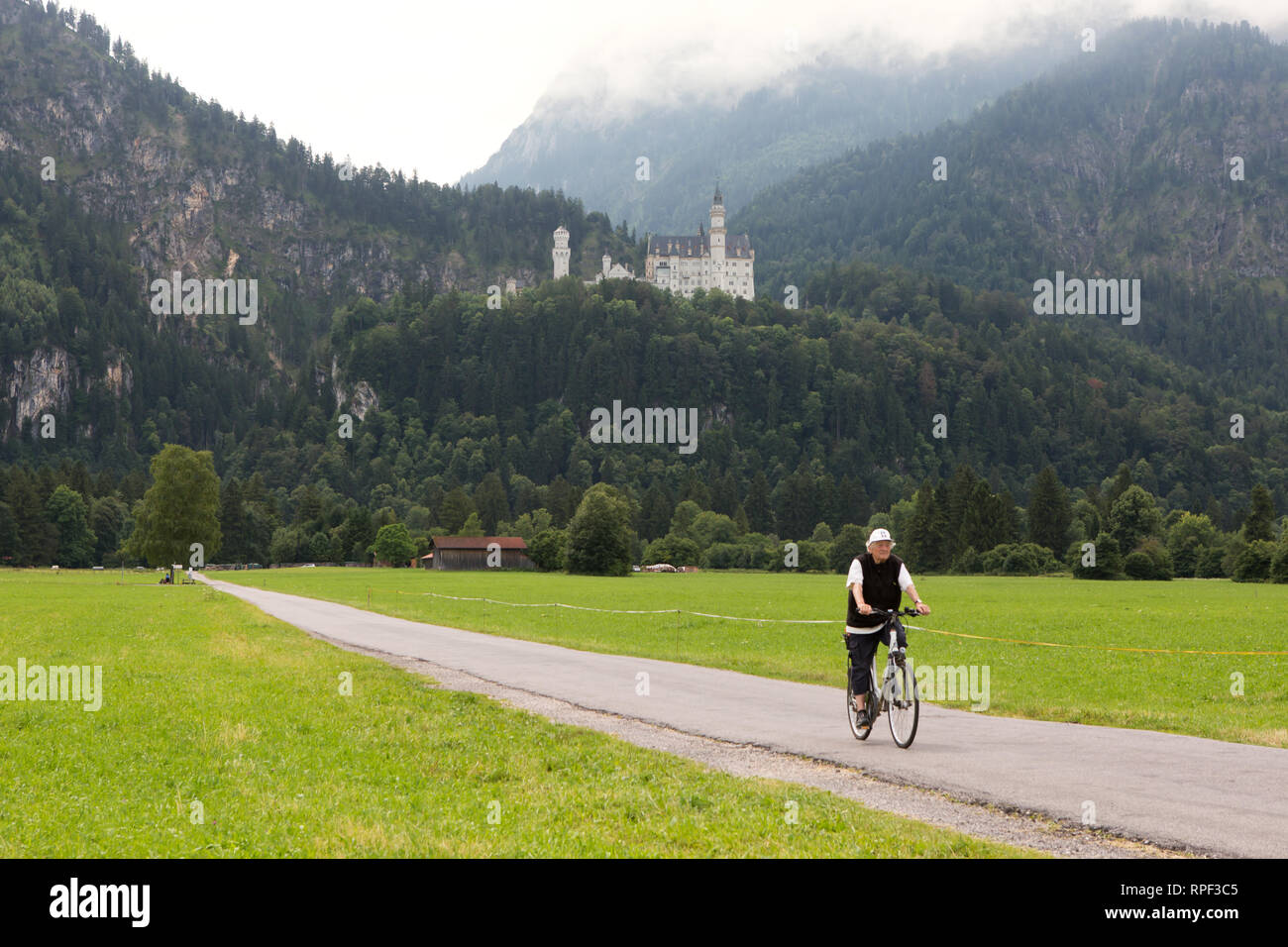 SCHWANGAU - Radfahrer mit dem berühmten Schloss Neuschwanstein im Hintergrund. Stockfoto