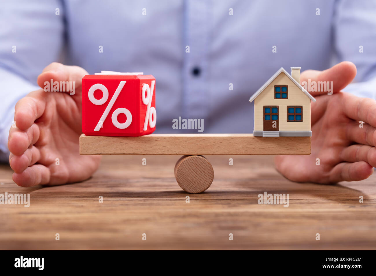 Der Unternehmer schützende Hand Balance zwischen Prozentsatz Rot Cubic Block und Haus Modell auf der Wippe Stockfoto