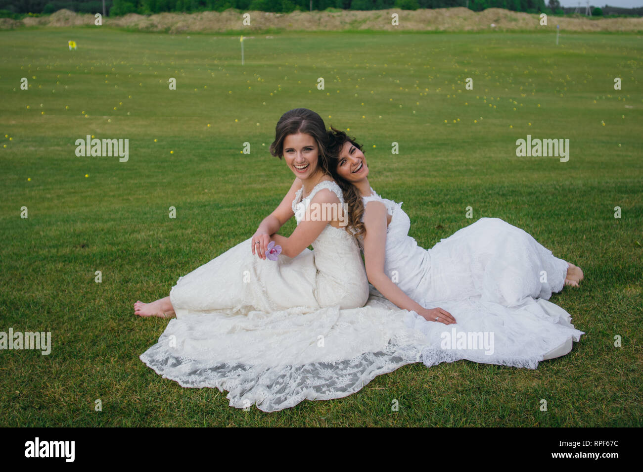 Zwei schöne Bräute Rücken an Rücken sitzen auf den grünen Bereich des Golf Club Stockfoto