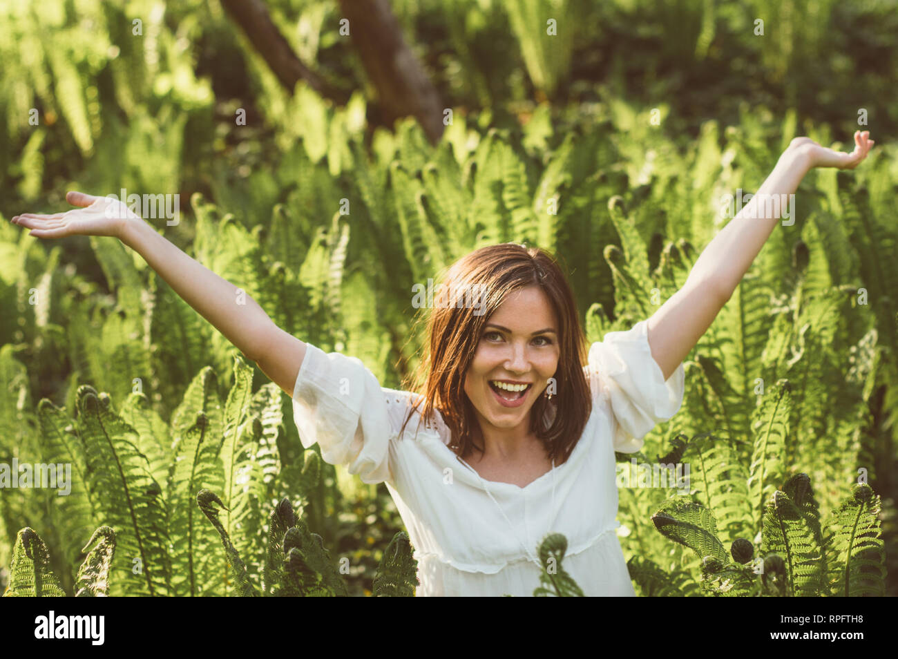 Schöne Freude brünette Mädchen Hände in Farn, Sonnenlicht Stockfoto