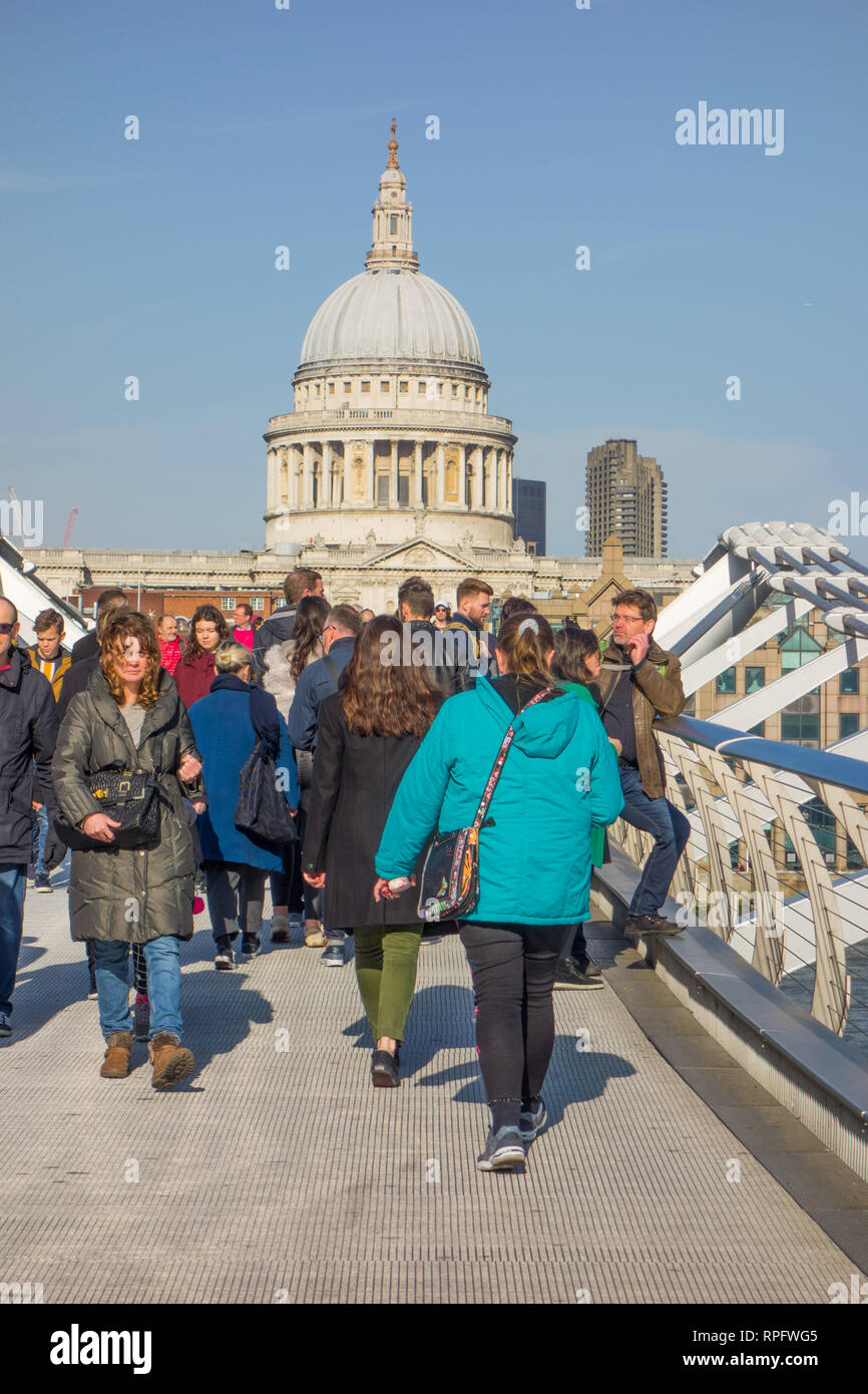 Männer Frauen Menschen zu Fuß über die Millennium Bridge in Richtung St Paul's Cathedral überspannt den Fluss Themse London England Großbritannien mit blauer Himmel Stockfoto