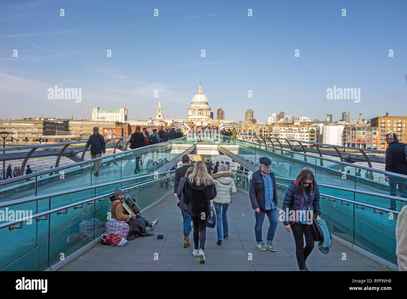 Männer Frauen Menschen zu Fuß über die Millennium Bridge in Richtung St Paul's Cathedral überspannt den Fluss Themse London England Großbritannien mit blauer Himmel Stockfoto