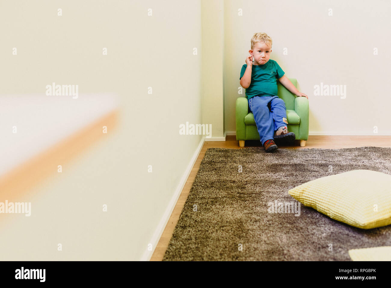 Zwei Jahre alter Junge allein in einem Sessel. Stockfoto