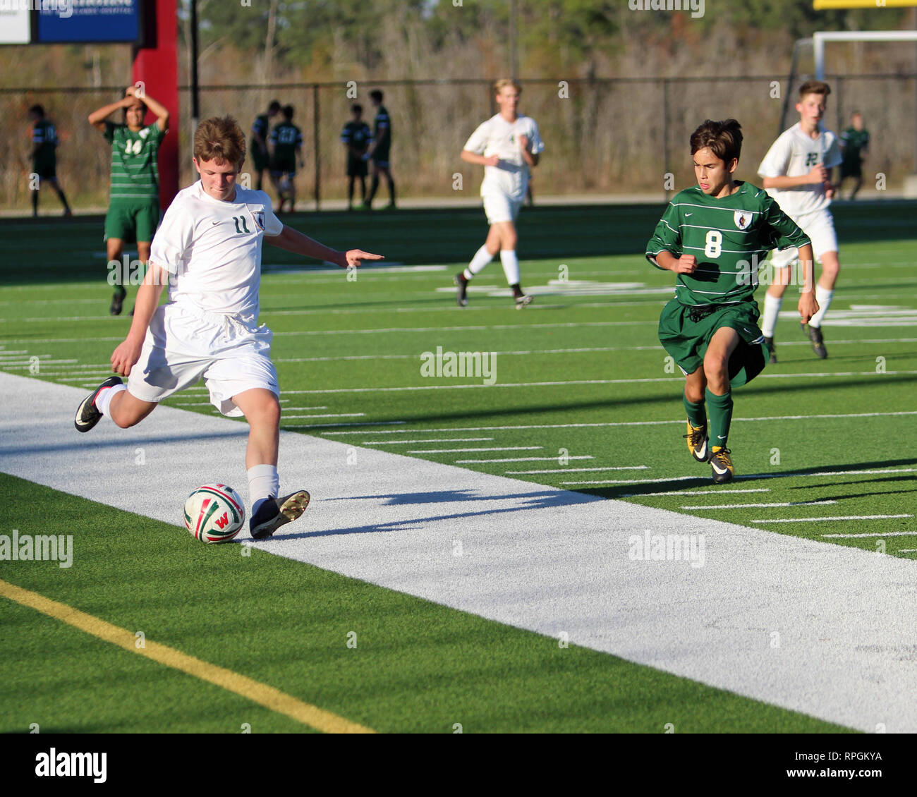 Spieler dribbelt auf der rechten Seite des Feldes und überquert den Ball in der High School Jungen Fußball Aktion auf Woodforest Bank Stadium in Shenandoah, Texas. Stockfoto