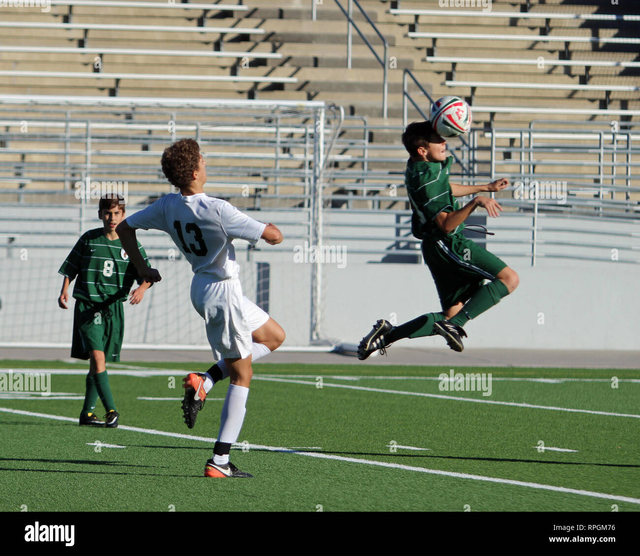 Fußball-Spieler springt in die Luft für eine Kopfzeile in der High School Jungen Fußball Aktion auf Woodforest Bank Stadium in Shenandoah, Texas. Stockfoto