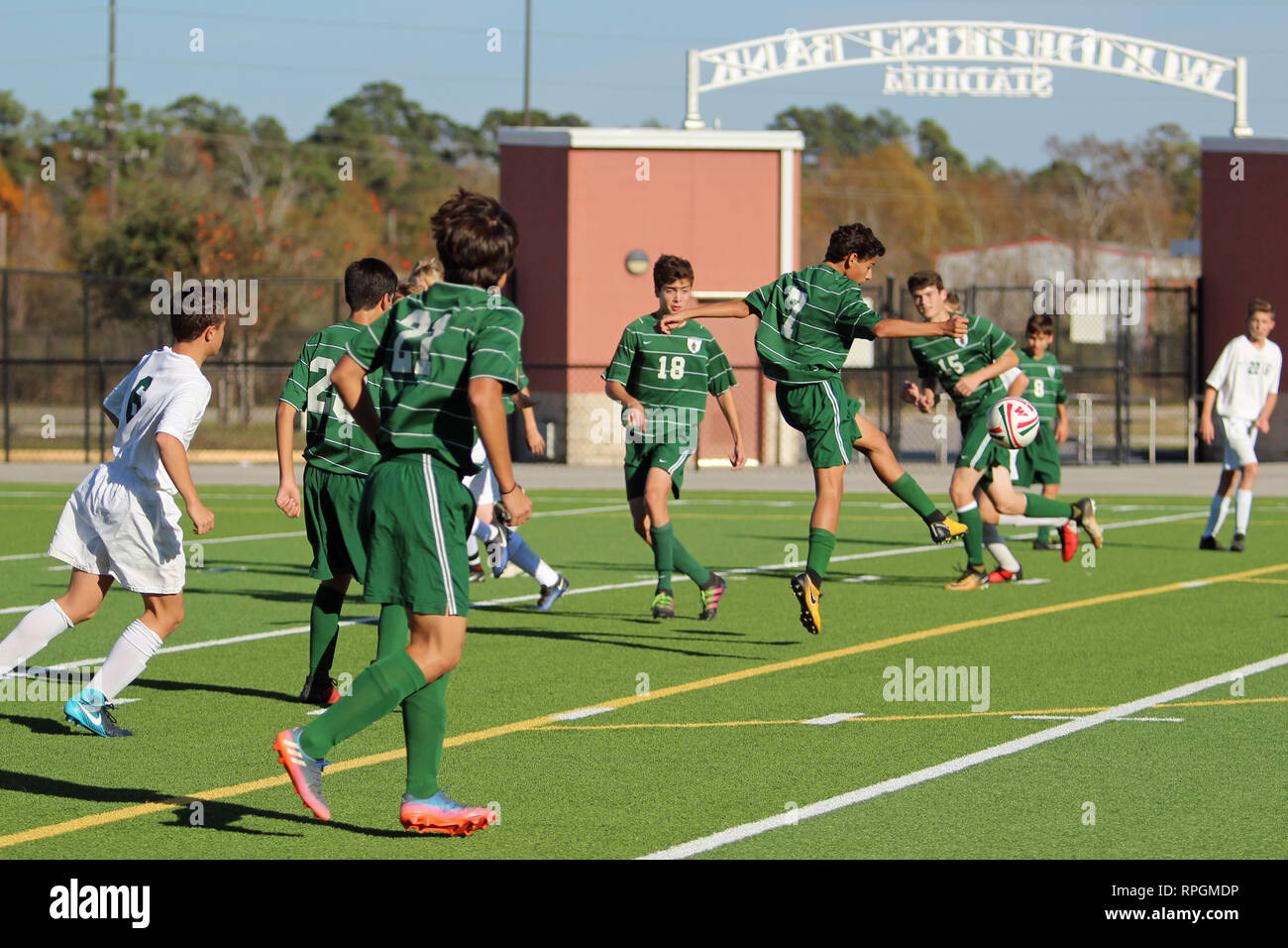 Defender löscht, die Fußball in der High School Jungen Fußball Aktion auf Woodforest Bank Stadium in Shenandoah, Texas. Stockfoto