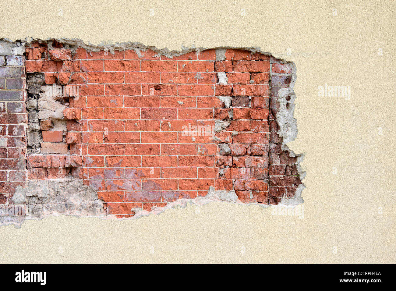 Stuck Außenwand mit freiliegenden oder beschädigten Bereich enthüllt verwitterten alten Ziegel Muster, geeignet für einen Hintergrund mit Kopie Raum oder Copyspace. Stockfoto