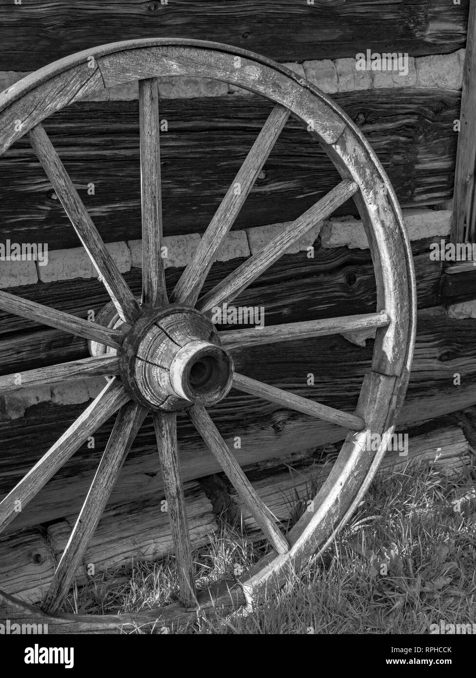 Verwitterte antikes Wagenrad gegen eine alte Scheune mit Split schiefen anmelden und Bau Ritze. Stockfoto