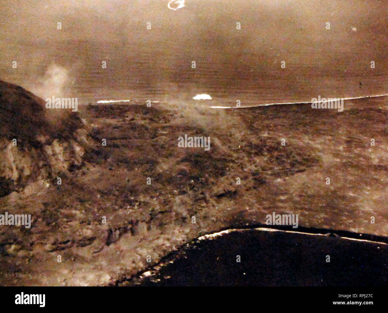 Schlacht um Iwo Jima, Februar-März 1945. Mt. Suribachi auf Iwo Jima. Schäden durch naval Geschützfeuer und Bombenangriffe zufügte, können entlang Bluff und am Strand gesehen werden. Mit dem Flugzeug von USS Makin Island (CVE 93) am D-Day, 19. Februar 1945 fotografiert. Stockfoto