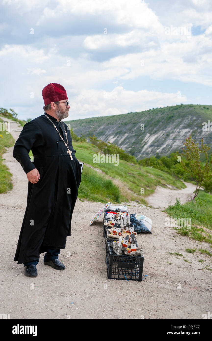 Ein Priester verkauf Nippes an Touristen außerhalb des Orhei Vechi Höhle Kloster in der Republik Moldau. Stockfoto