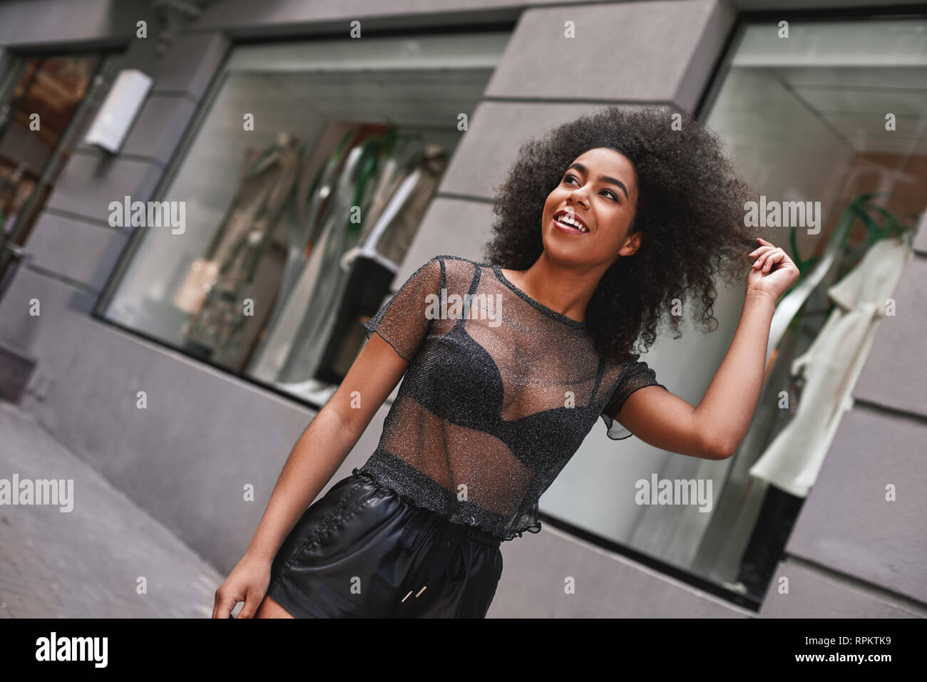 Unglaublich schön. Schöne afro-amerikanische Frau in Leder Hosen das Spielen mit ihrem Haar, während auf der Straße. Fashion Look Stockfoto
