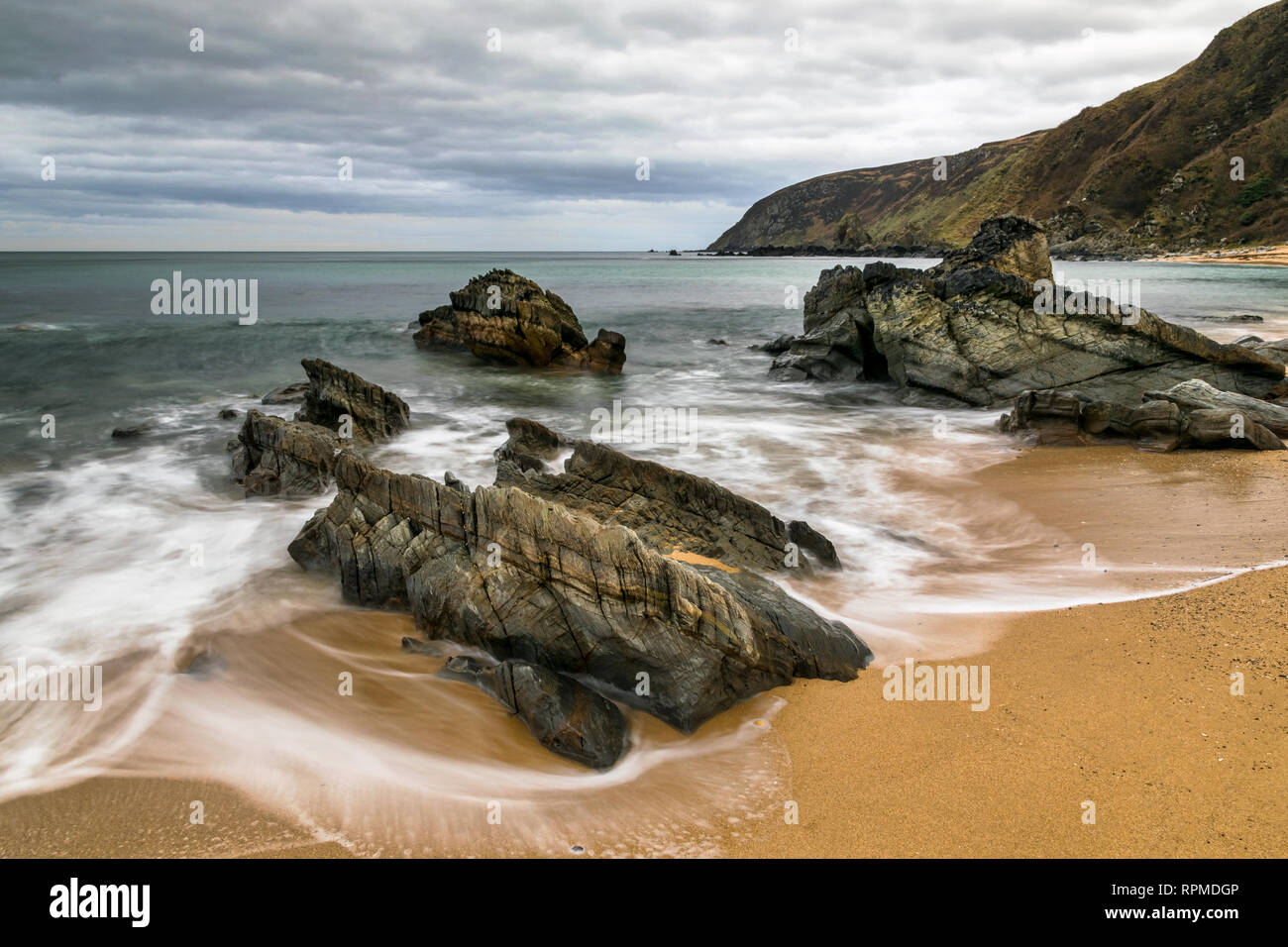 Dies ist eine lange Belichtung Foto von Wellen, die durch Felsen auf einen Sandstrand. Dies wurde auf Kinnago Bay in Donegal Irland Stockfoto