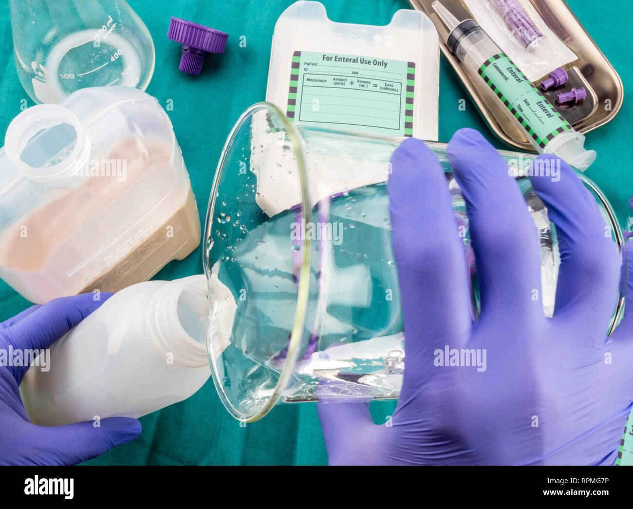 Krankenschwester Verdünnung mit Wasser auf die enterale Ernährung Flasche, Palliative Care, konzeptionelle Bild, horizontale Zusammensetzung Stockfoto