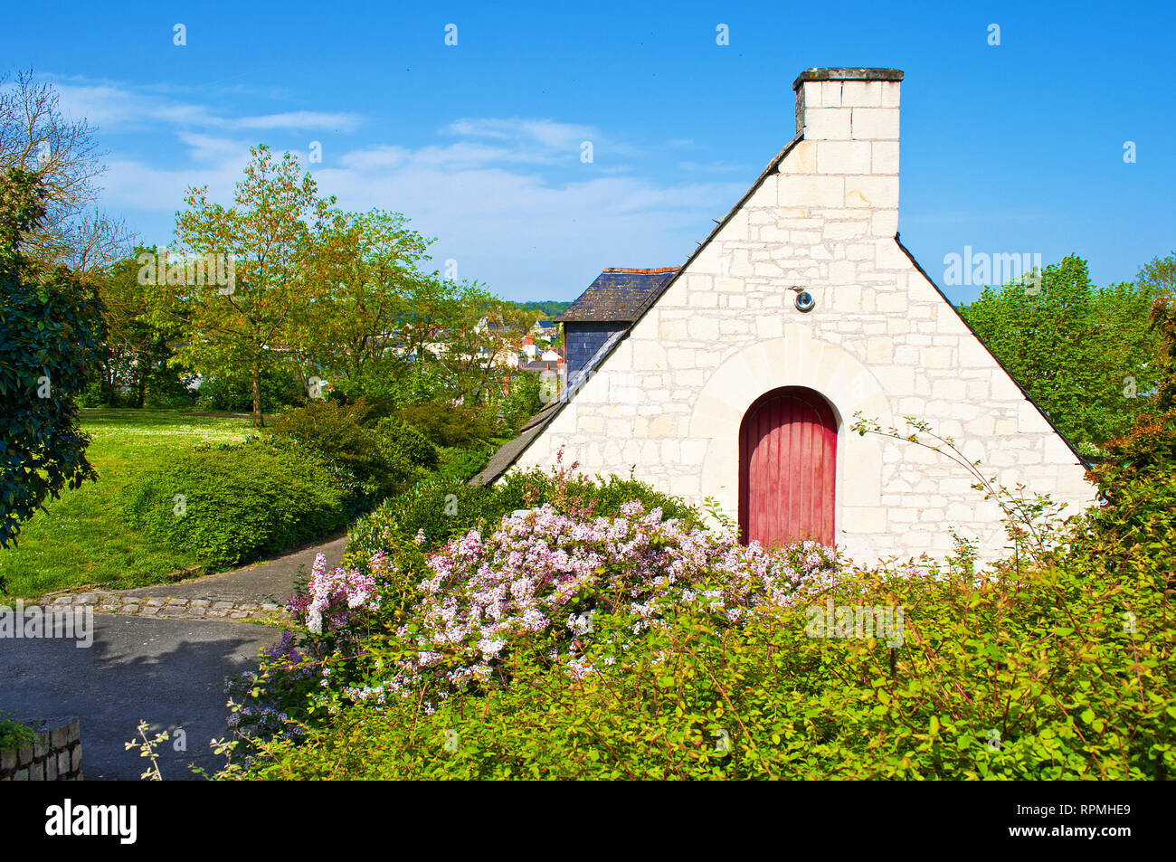 Ein kleines Haus mit dreieckigen Dach und gewölbte rote Holztür in erstaunlich kleinen Stadt Saumur, Frankreich. Viele grüne Bäume und rosa Blüten. Warme autolöscher Stockfoto