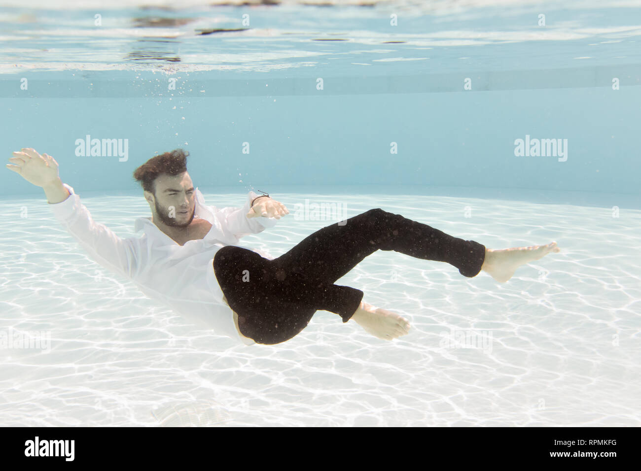 Ein junger Mann floating Underwater während voll bekleidet Stockfoto