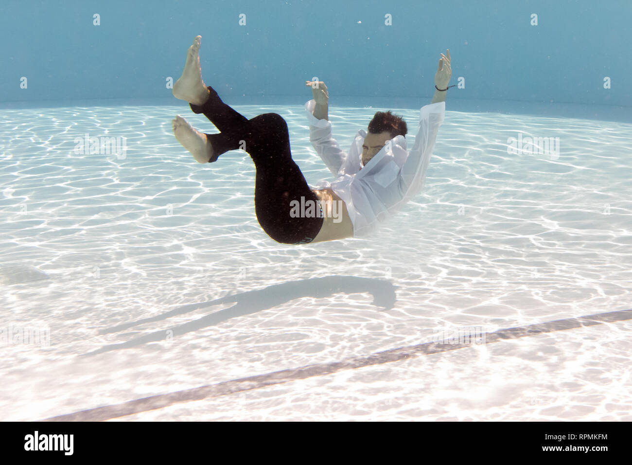 Ein junger Mann versinkt in einem Pool während voll bekleidet Stockfoto