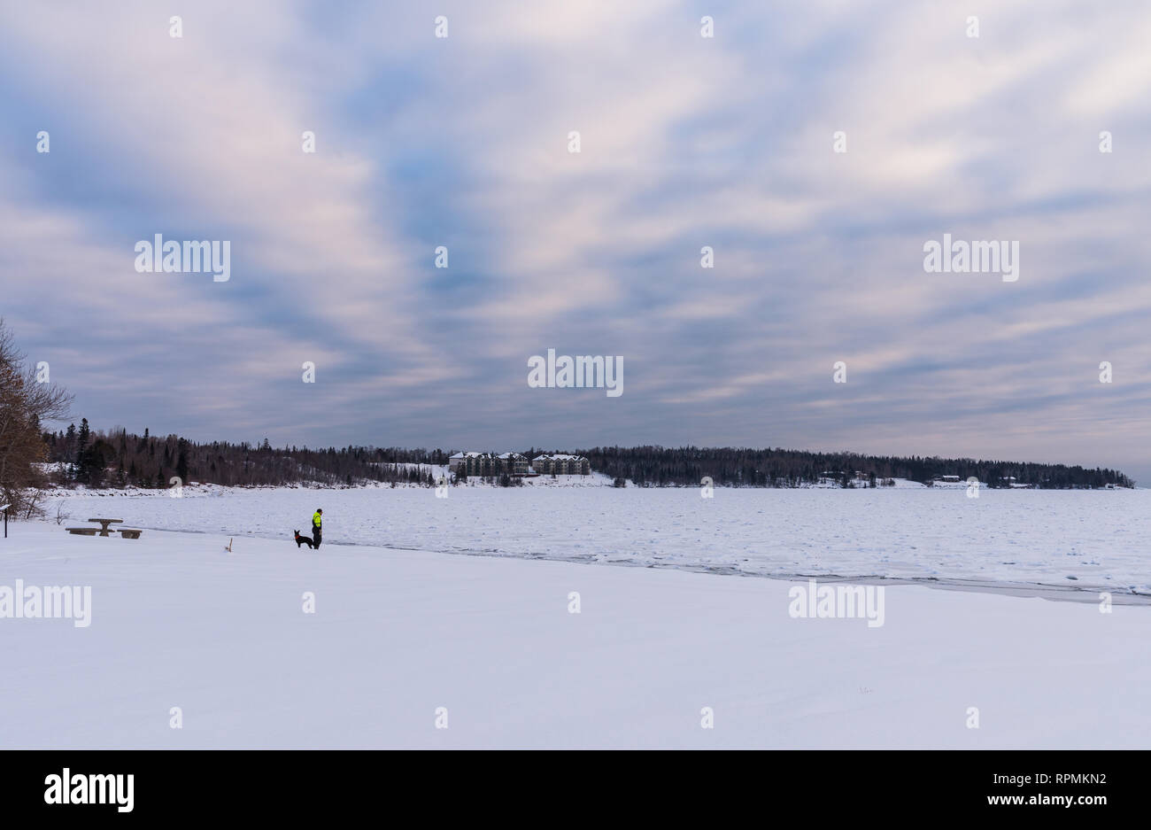 Ein Mann, der seinen Hund am Ufer des eisigen Lake Superior. Zwei Häfen, Minnesota, USA. Stockfoto