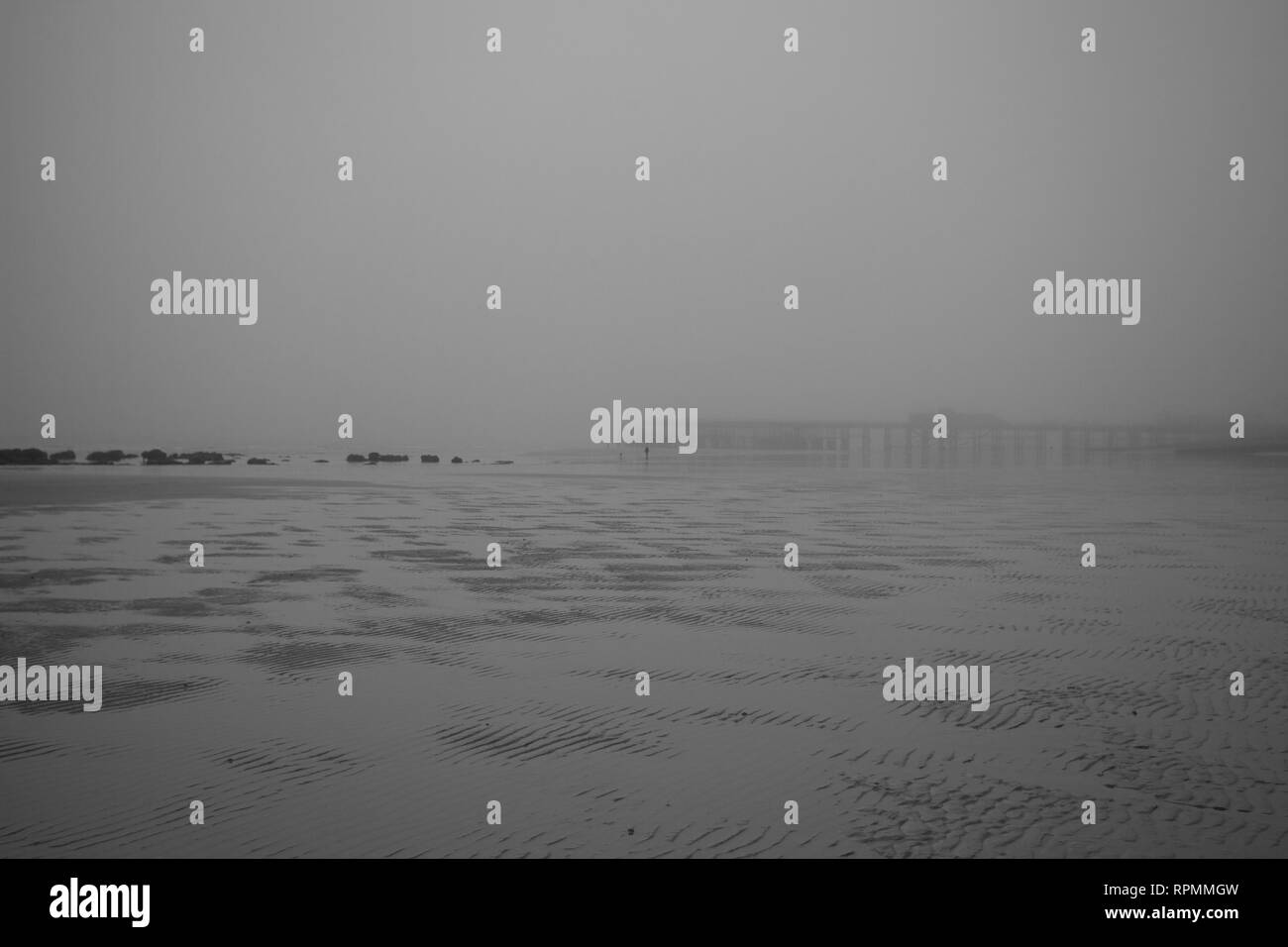 Hastings Strand bei Ebbe mit dem Pier in der Ferne während einer sehr nebligen Tag im Februar, East Sussex, Großbritannien Stockfoto