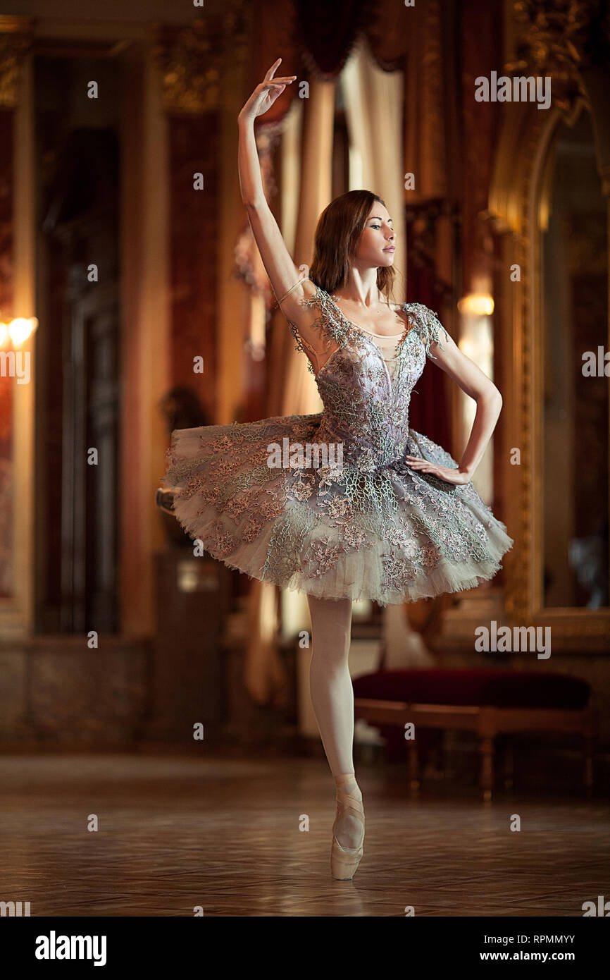 Schöne ballerina Tanz in der Halle gegen das luxuriöse Interieur. Arabesque Ballett dar. Stockfoto