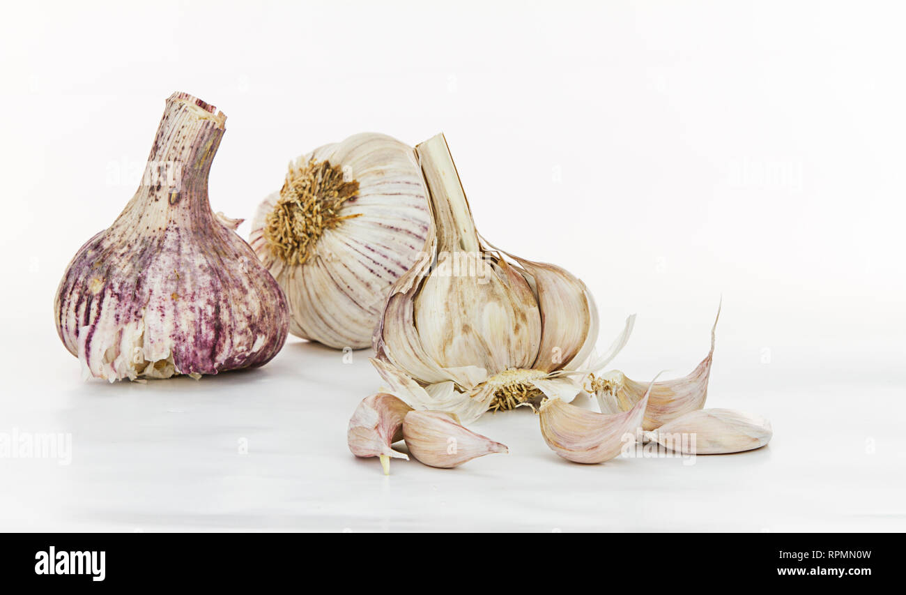 Close-up noch Leben der drei roten Knoblauch Zwiebeln, zwei ganze und ein mit ihren Zehen in der Frontseite geöffnet, auf weißem Hintergrund Stockfoto